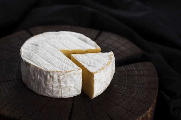 Sýr camembert na černém pozadí dřevěná, s kopií prostoru. Malá hloubka ostrosti — Stock fotografie