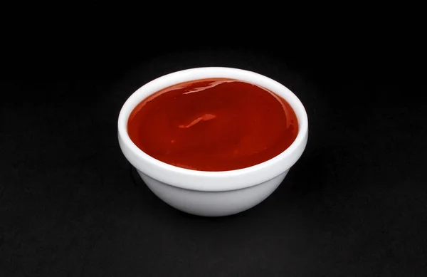 Ketchup in witte kom op zwarte achtergrond — Stockfoto