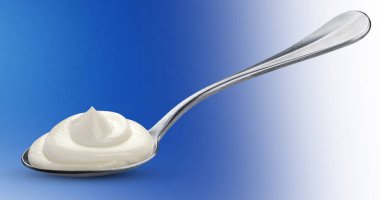 Üzerinde mavi arka plan izole kaşığı ekşi krema