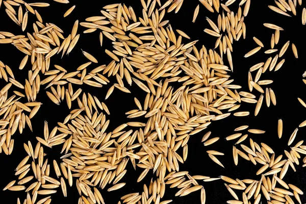 一堆燕麦种子在黑色背景上, 顶部视图 — 图库照片