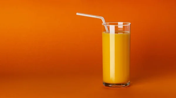 Um copo de suco de laranja no fundo laranja com espaço de cópia — Fotografia de Stock