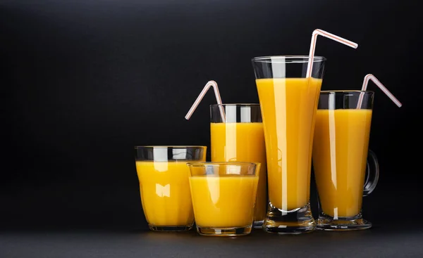 Vasos de jugo de naranja sobre fondo negro con espacio para copiar — Foto de Stock