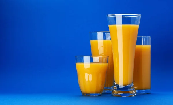 Vasos de jugo de naranja sobre fondo azul con espacio para copiar —  Fotos de Stock
