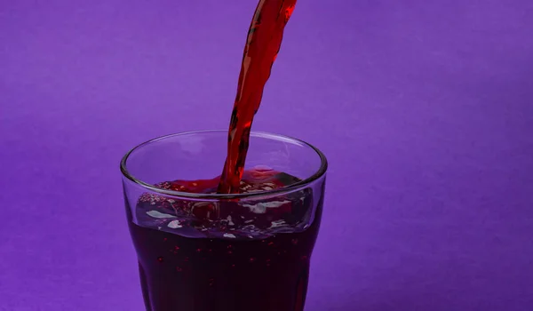 Jus de cerise versé dans le verre, isolé sur fond violet, avec espace de copie — Photo