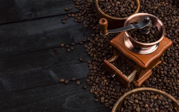Café molido, molino de café, tazón de granos de café tostados sobre fondo de madera negro, vista superior —  Fotos de Stock