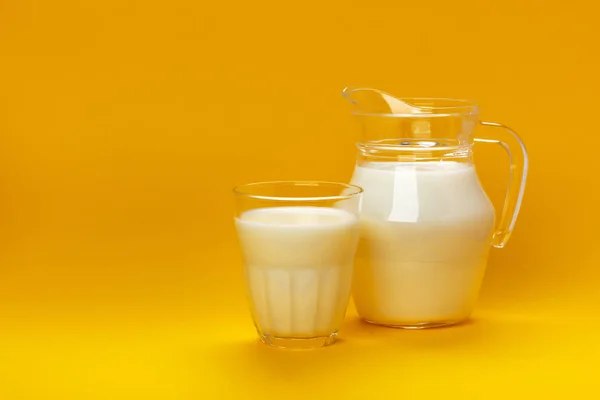 Tarro y vaso de leche aislados sobre fondo amarillo con espacio de copia para texto, concepto de productos lácteos —  Fotos de Stock