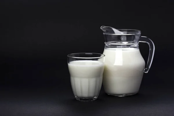 Tarro y vaso de leche aislados sobre fondo negro con espacio de copia para texto, concepto de producto lácteo —  Fotos de Stock