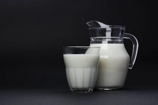 Vaso e bicchiere di latte isolato su fondo nero con spazio per la copia del testo, concetto di latticini — Foto Stock