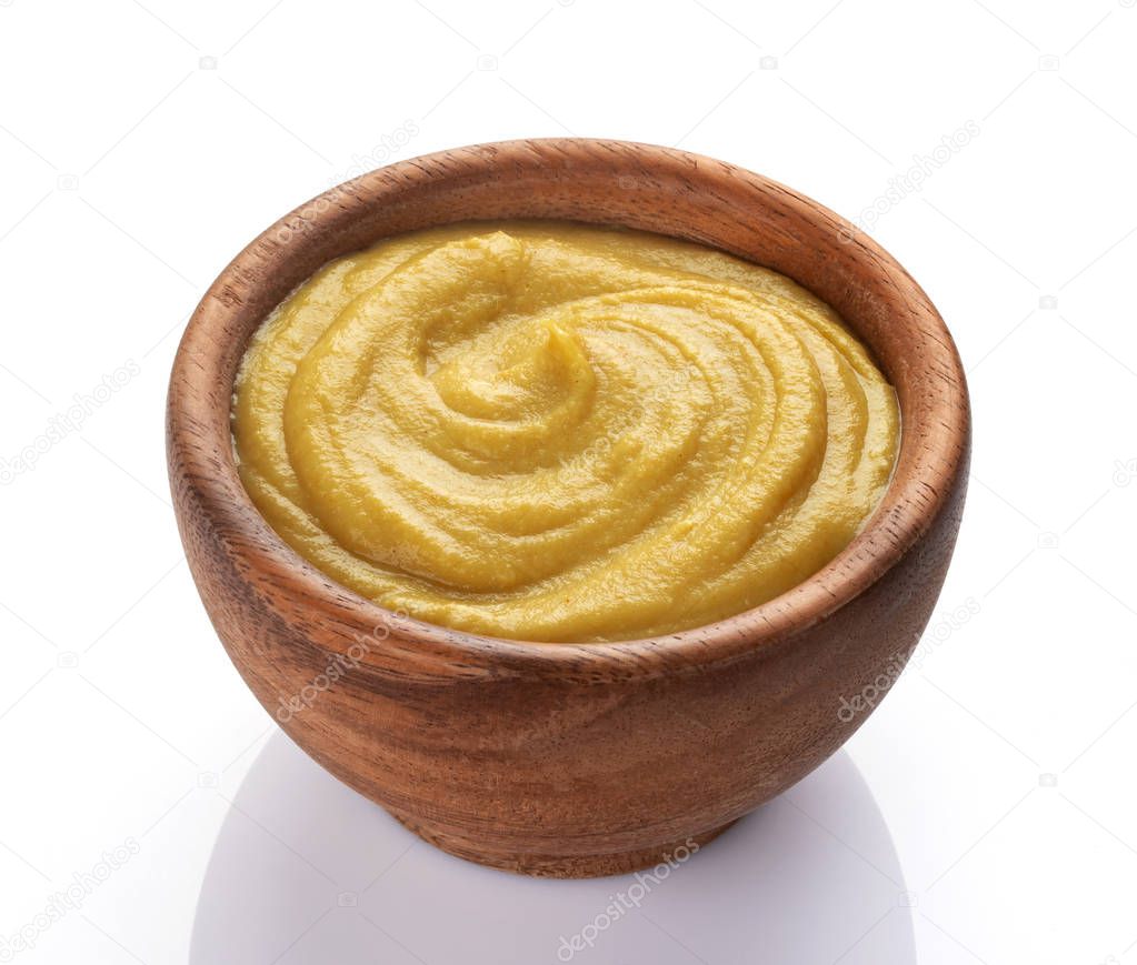Mustard sauce in wooden bowl isolated on white background
