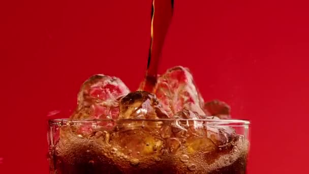 Cola mit Eiswürfeln übergießen. Cola-Limo mit Blasen aus nächster Nähe. Zeitlupe — Stockvideo