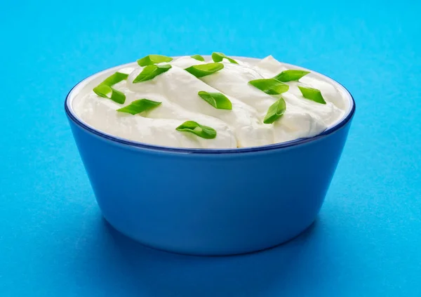 Bowl of sour cream on blue background — Stock Photo, Image