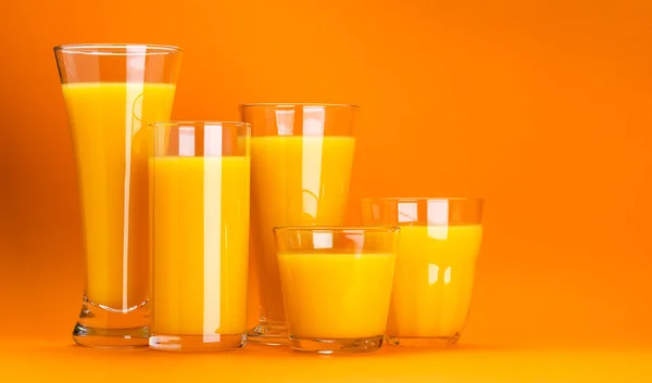 Orange juice isolated on colour orange background with copy space for text, glasses of fresh citrus cocktail, healthy drink concept
