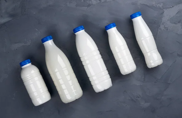 Insamling av mjölkflaskor på grå sten bakgrund, ovanifrån — Stockfoto