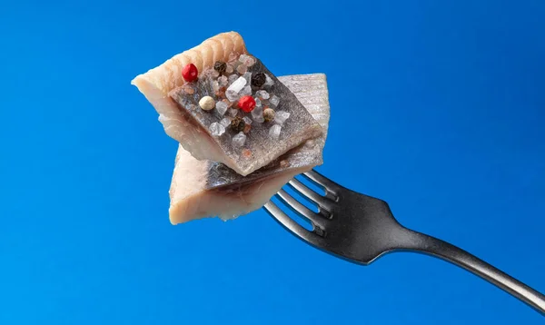 在蓝底分离出来的叉子上的咸鲱鱼片 熏鱼片 — 图库照片