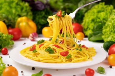 Bir tabak İtalyan makarnası, çatallı spagetti domates ve fesleğen yapraklı.