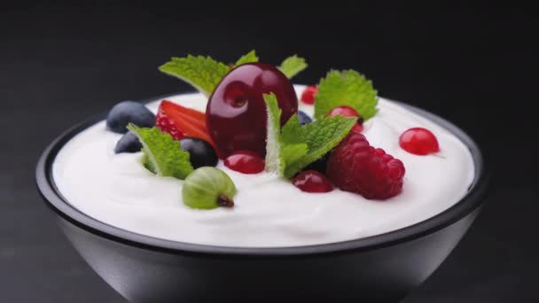 Чаша йогурта с дикими ягодами на черном фоне — стоковое видео