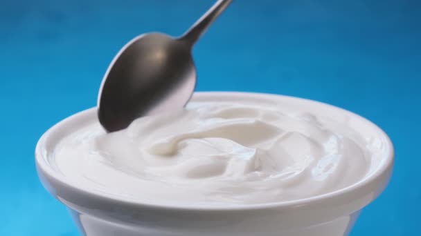 Skål av gräddfil på blå bakgrund, grekisk yoghurt — Stockvideo