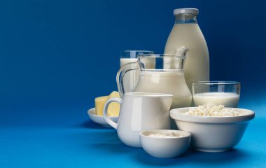 Mavi arka planda süt ürünleri, çeşitli süt, kefir, ekşi krema ve yoğurt.
