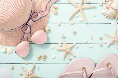 pembe güneş gözlüğü, şapka, flip flop ve kabukları mavi ahşap tahta üzerinde