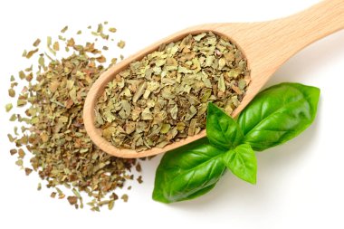 Beyaz arka plan üzerinde izole tahta kaşık kuru fesleğen yaprağı