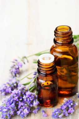 Lavender essential oil in the amber bottle, with fresh lavender flower heads. clipart