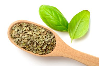 Beyaz arka plan üzerinde izole tahta kaşık kuru fesleğen yaprağı