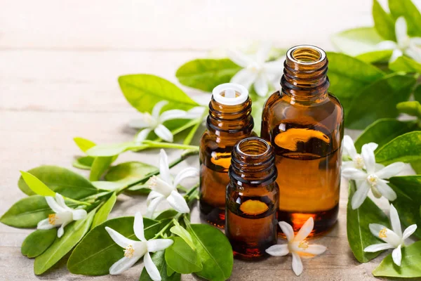 neroli esans kahverengi cam şişede taze beyaz neroli çiçek ve yeşil yaprakları ile.