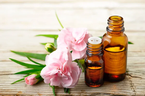 Karanfil mutlak esans ve ahşap tahta üzerinde pembe çiçekler