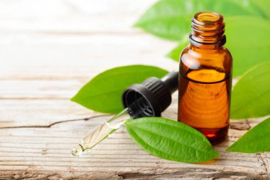 Tarçın yağı ve ahşap masa üzerinde taze tarçın yaprakları