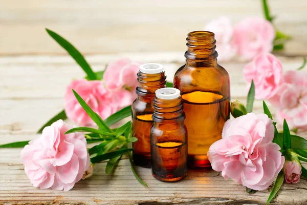 Karanfil mutlak esans ve ahşap tahta üzerinde pembe çiçekler