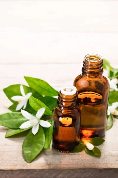 neroli esans kahverengi cam şişede taze beyaz neroli çiçek ve yeşil yaprakları ile.