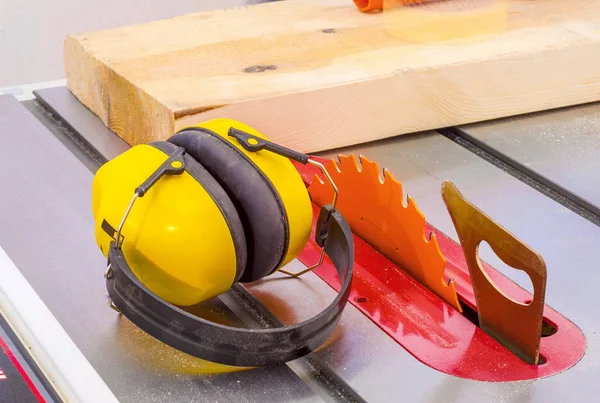 Circular wood saw in the carpentry workshop and hearing protection against noise at work