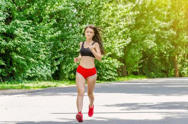 girl in red shorts is running in the park