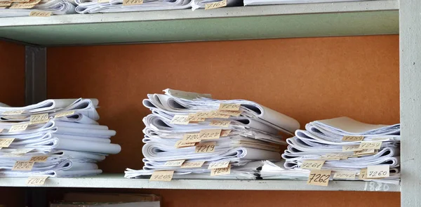 Ofiste raflardaki eski belgeleri, çizimleri numaraları ile yığılmış
