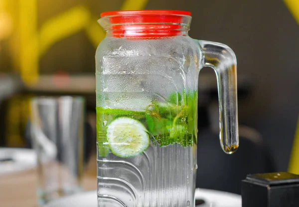 Mojito drink in a steamed glass jug, lime, mint
