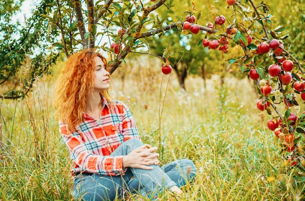 Charmante femme aux cheveux roux, portrait dans le jardin de pommes sur le dos — Photo