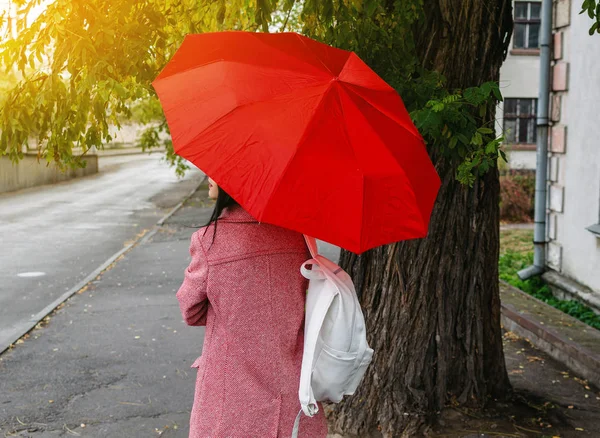 Girl under a red umbrella in the city