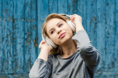 Sevimli kız eski tahta arka plan üzerinde beyaz kablosuz kulaklık müzik dinlemek. Elektronik müzik. Müzik tarzı. Kulağa hoş geliyor. Ses keyfi.
