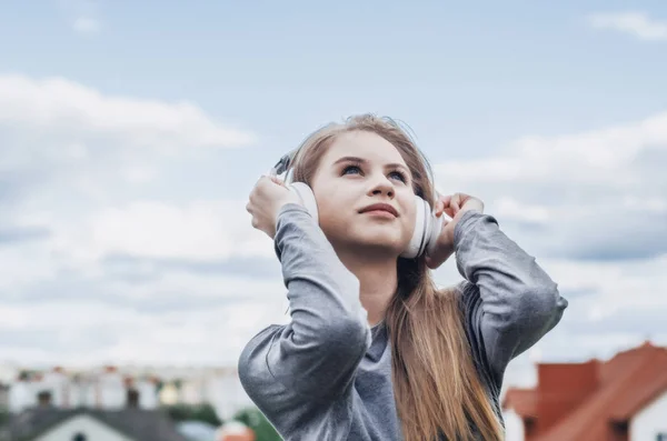 Νεαρή Κοπέλα Ακούει Μουσική Λευκά Ακουστικά Κρατώντας Χέρια Ανοιχτόχρωμο Φόντο — Φωτογραφία Αρχείου