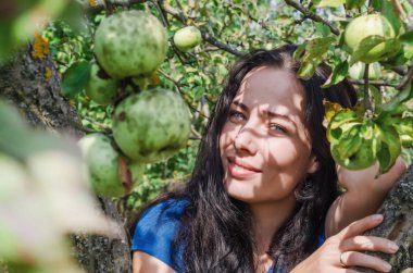 Elma meyve ağaçlarının dalları arasında siyah saçlı kız. Sağlıklı gıda. Eva stili