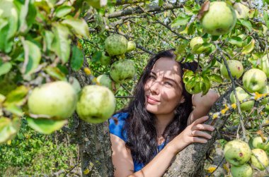 Elma meyve ağaçlarının dalları arasında siyah saçlı kız. Sağlıklı gıda. Eva stili