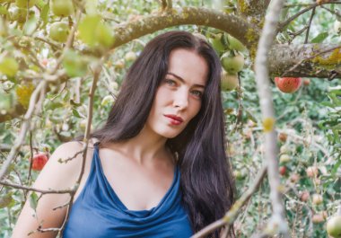 terk edilmiş bir bahçede elma ağaçlarının twigs tarafından çerçeveli bir ışık Yaz elbiseli kadın. Baştan çıkarma, cinsellik. Kadın sağlığı. Cennet