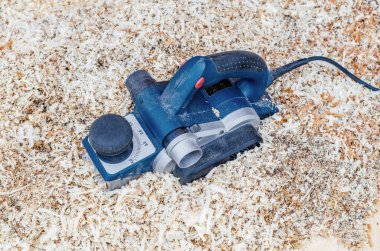 El ile Elektrikli Planya talaş içinde yatıyor. Ahşap. Ağaç ürünleri imalatı. Marangozluk aracı.