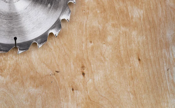 Circular metal saw on background polished plywood. Carpentry workshop, work tools