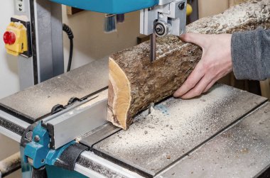 Doğrama atölyesinde çalışan günlük şerit testere kullanarak panoları keser. Sanayi. Ham Ahşap ahşap el sanatları. Fabrikada çalışmak.