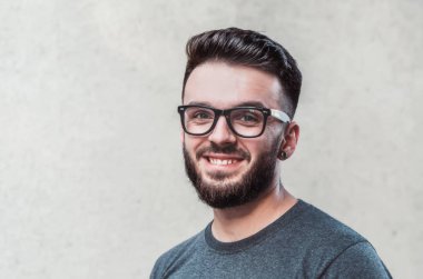 Gri arka planı ayakta yakışıklı genç adam portresi. Gençlik Kültür. Berber dükkanı.