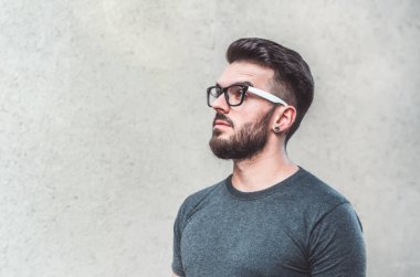 Gri arka planı ayakta yakışıklı genç adam portresi. Gençlik Kültür. Berber dükkanı.