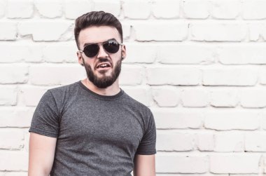 Yakışıklı genç adam beyaz duvara karşı ayakta portresi. Gülümseme.