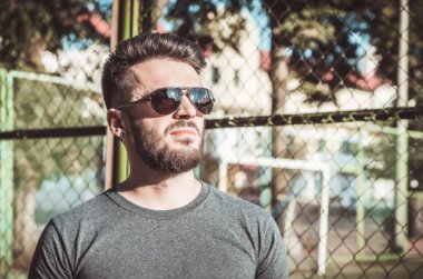 Sakal ve spor alanında, metal ızgara siyah gözlük ile şık genç adam portresi.