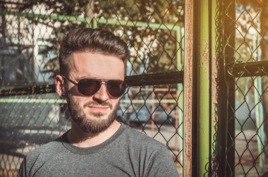 Sakal ve spor alanında, metal ızgara siyah gözlük ile şık genç adam portresi.